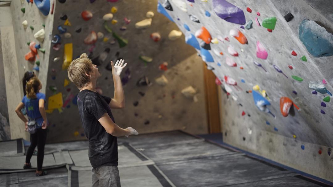Climbers have time to warm up and get motivated as they study bouldering routes for USA Climbing rock climbing competition at ACG